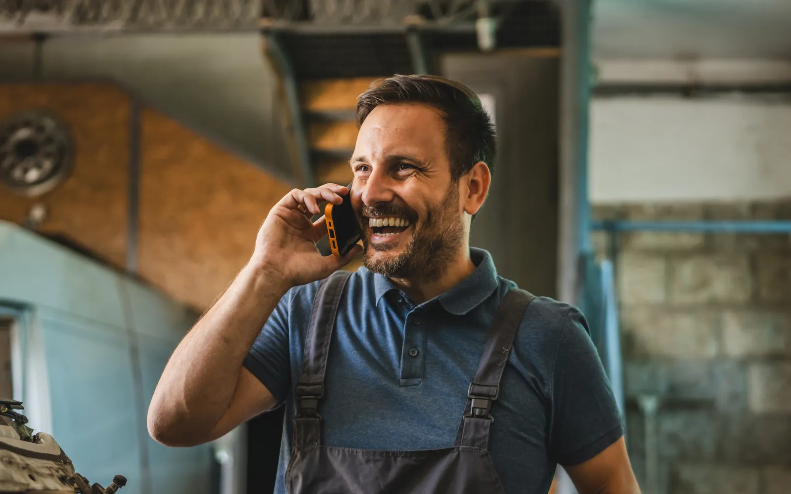 Smiling tradesman taking a call in his workshop